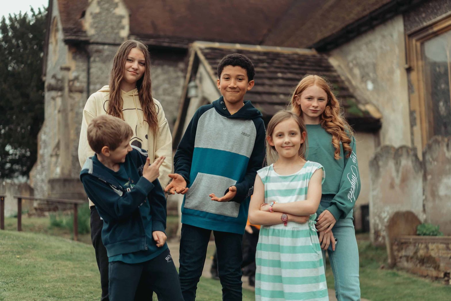 Five children standing outside a church having a laugh