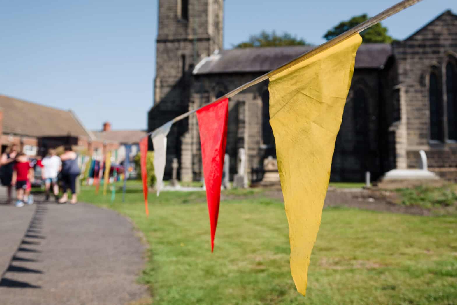 Colourful bunting strung along a path leading to a church in the background.