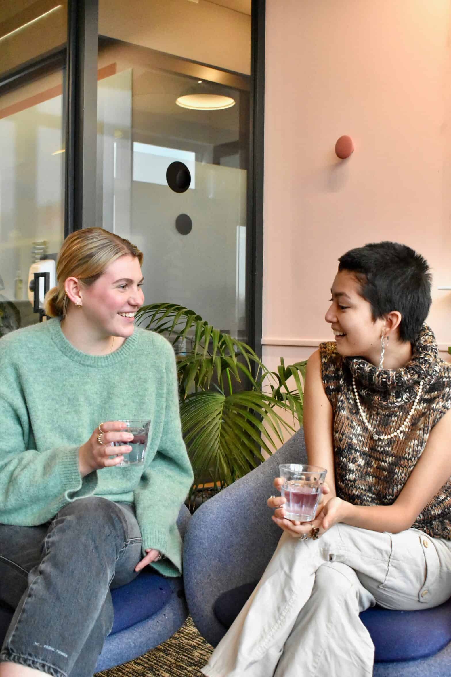 Two women talking with glasses of water in their hands