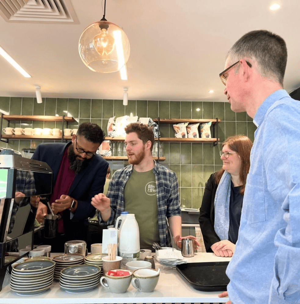 Four people in a trendy cafe making a coffee