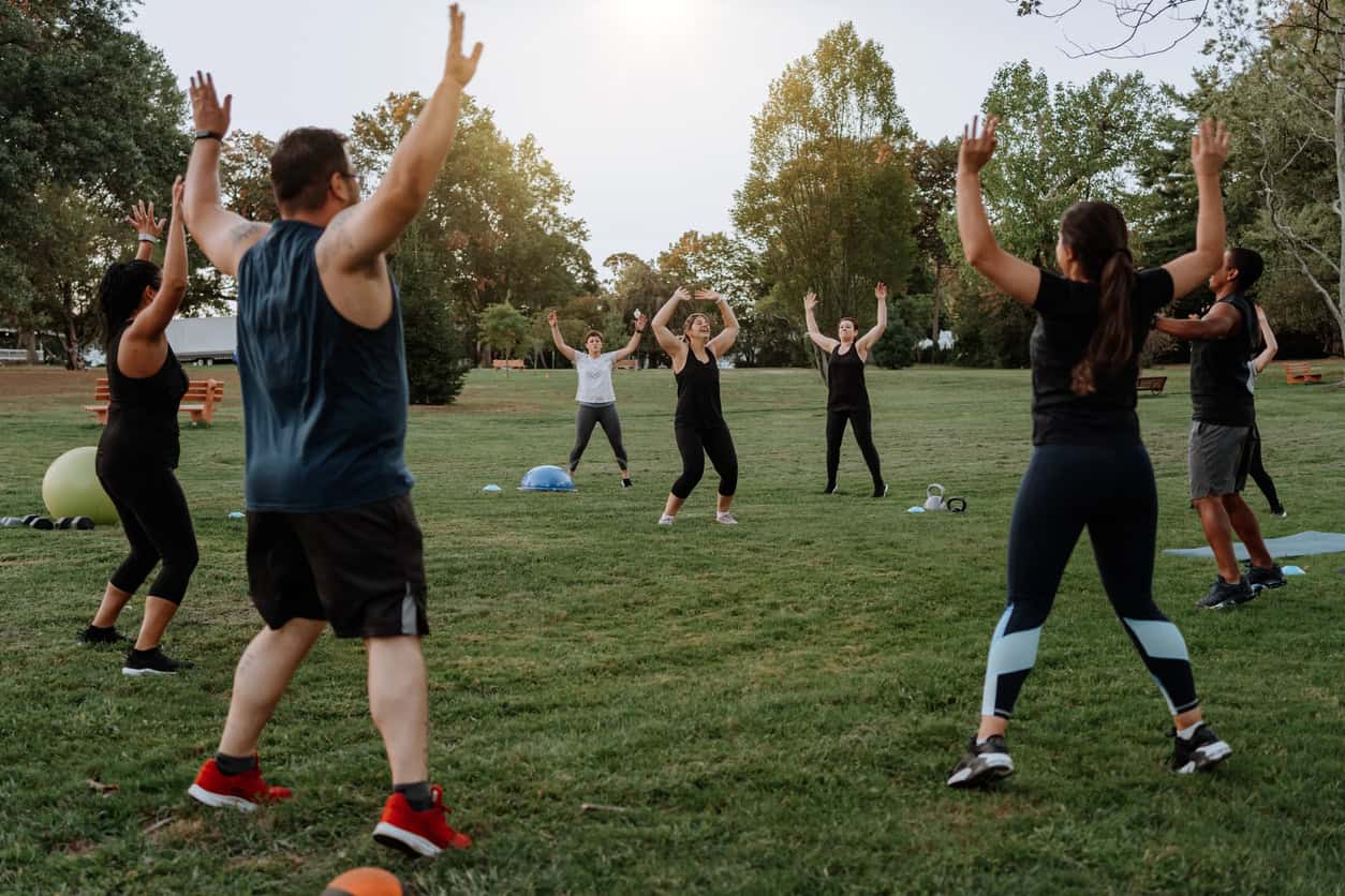 A group of adults doing keep fit in a park.