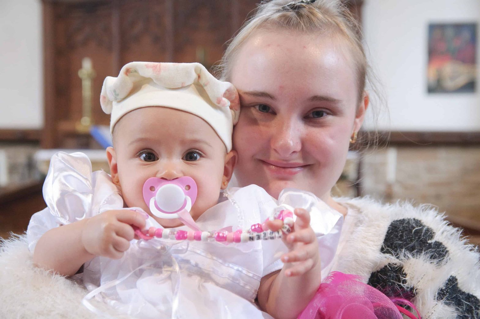 Close up of a mum smiling to the camera holding her baby's head near her head