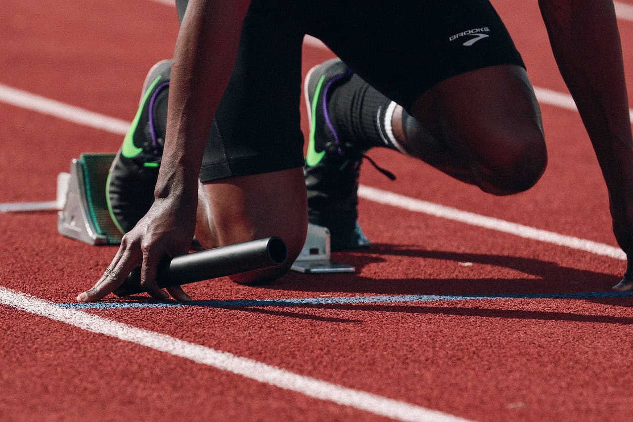 Close up of athlete feet and hands crouched at the start of a race on a running track
