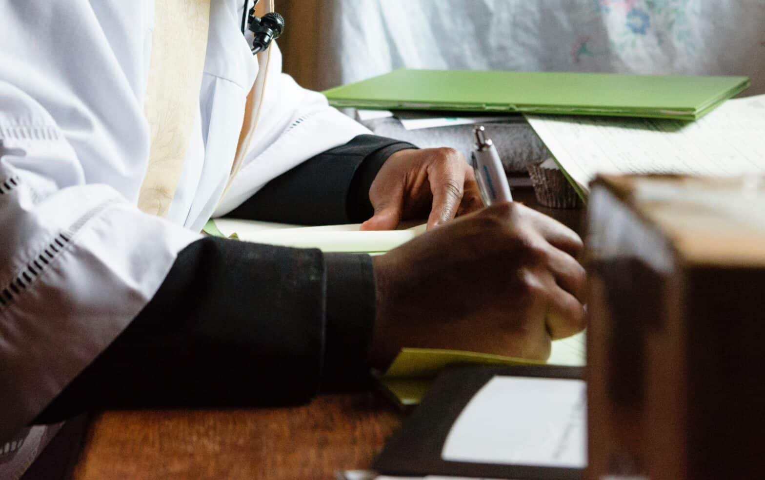 Close up of male vicar's hand holding a pen and writing.