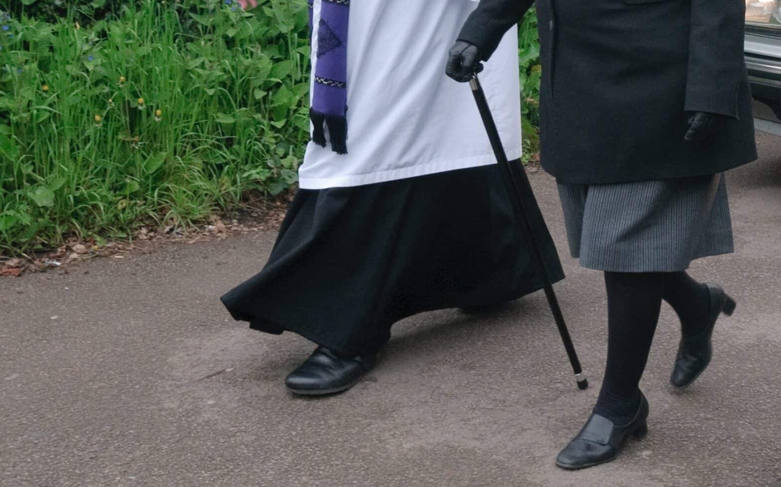 Close up of vicar and funeral director feet walking side by side