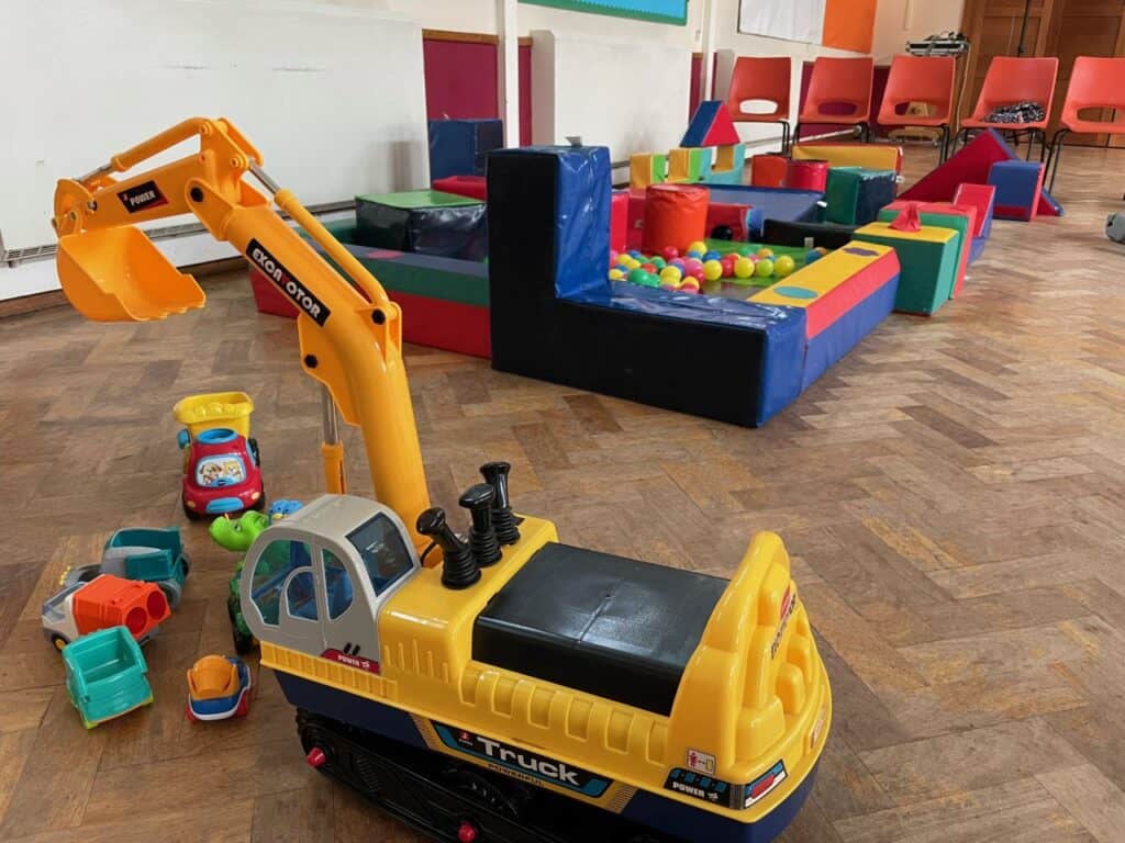 Colourful ball pool and toy tractor in a community hall.