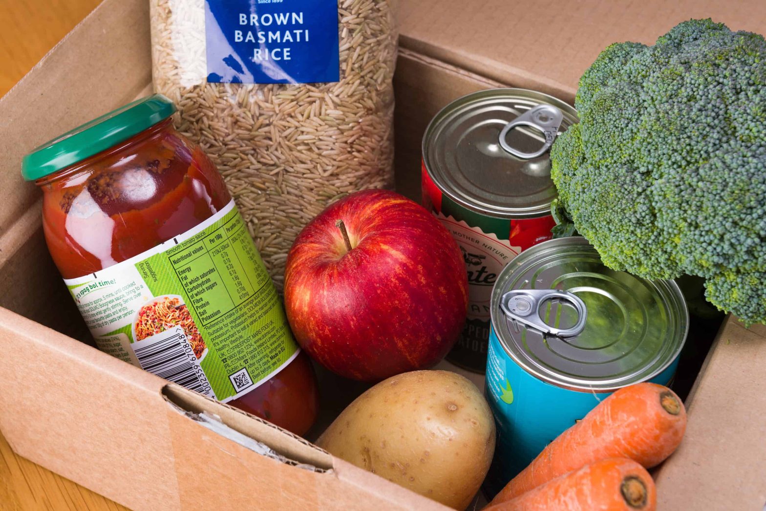 Fresh, tinned and packaged produce in a cardboard donation box.
