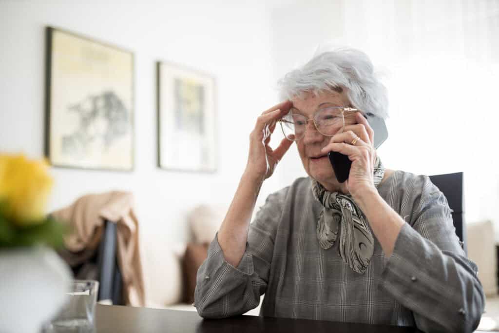Grey-haired older lady talking to someone on the phone.