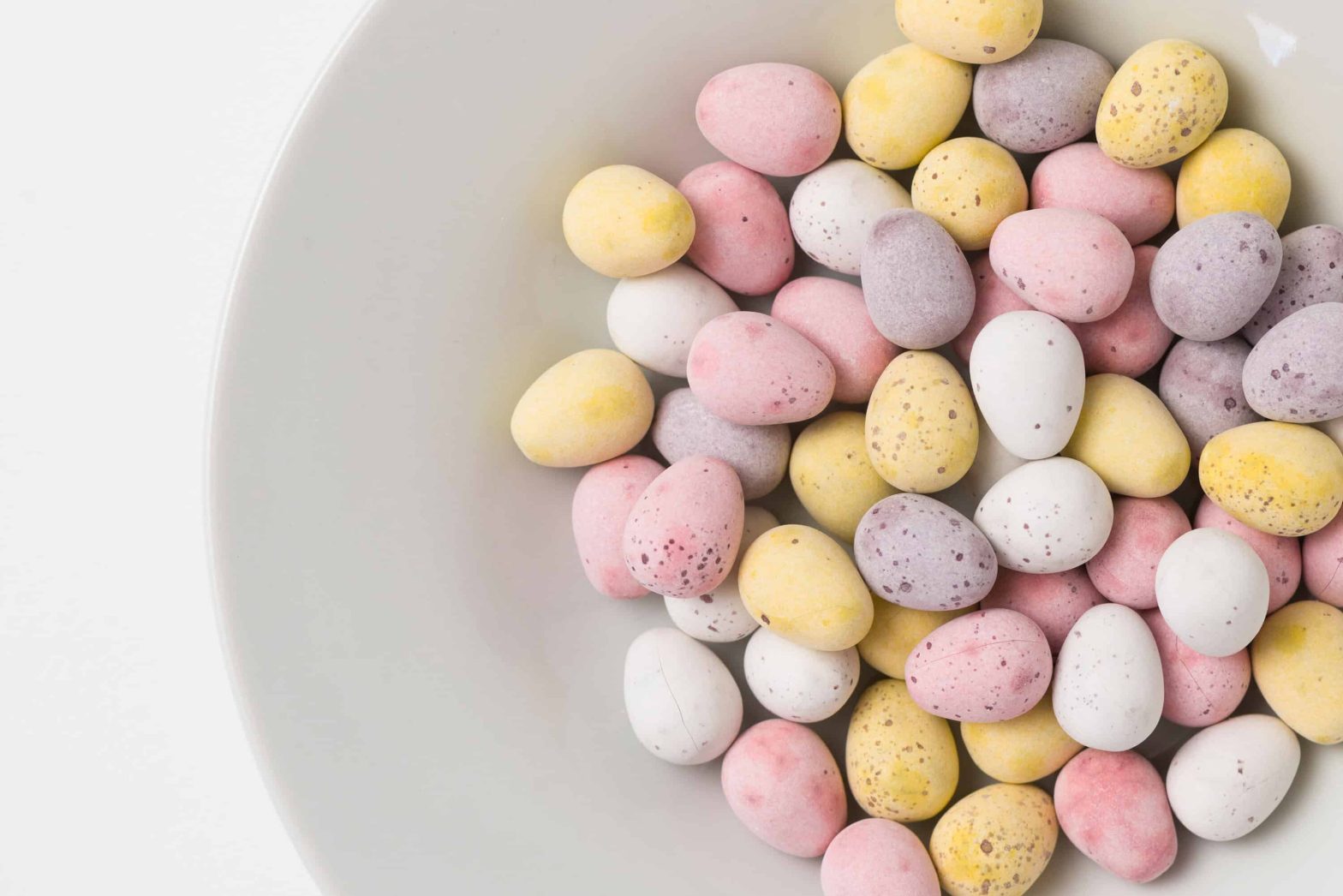 Lots of colourful chocolate mini eggs in a bowl.