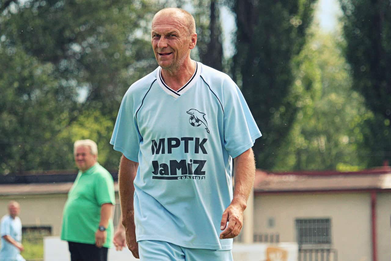 Mature men in football kit playing football in a park