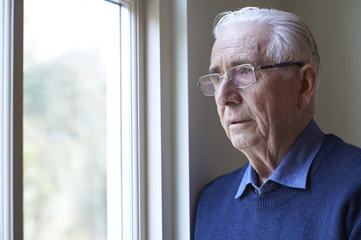 Older gentleman looking out of a window.