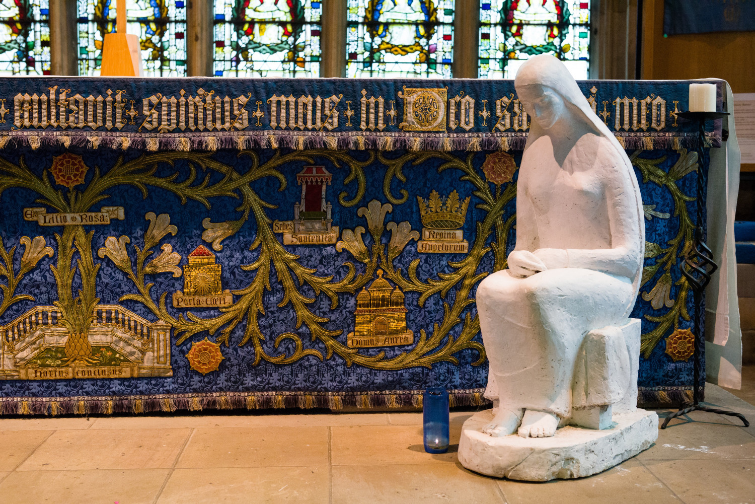 Pensive-looking white statue of sitting lone woman.