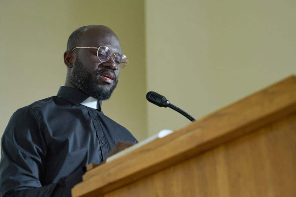 Priest speaking into a microphone on the podium in church