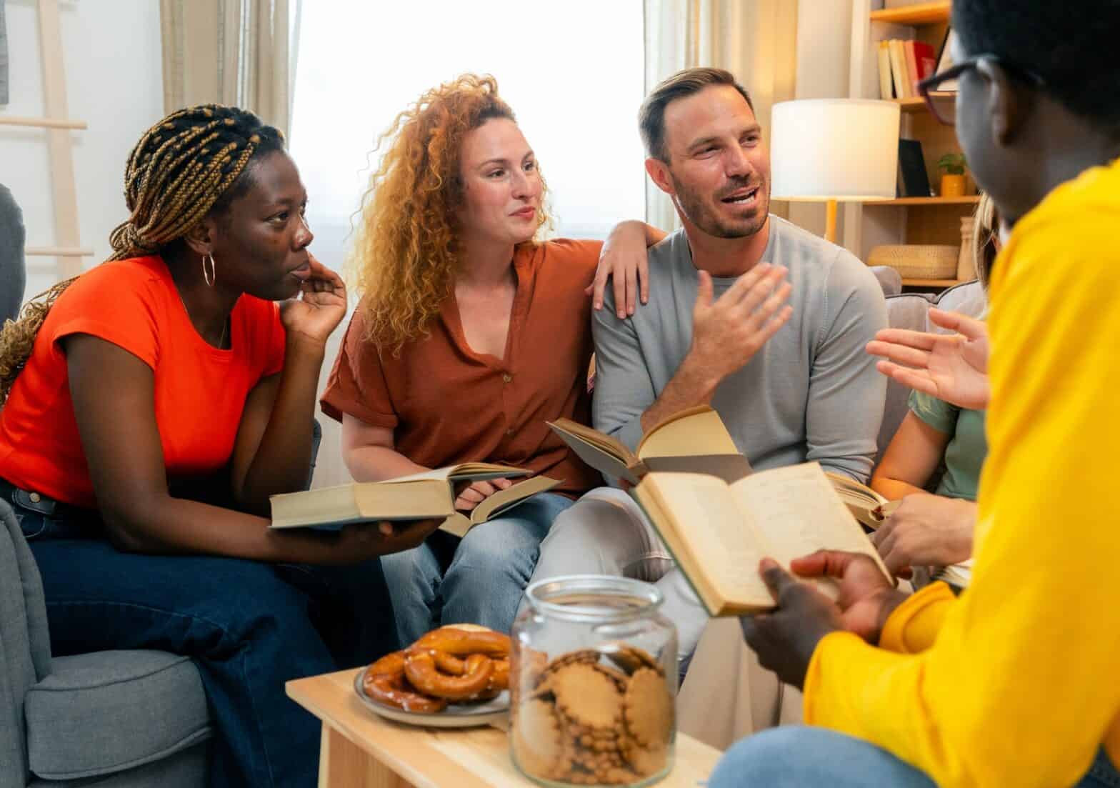 Two women and a man chatting over coffee at a table.
