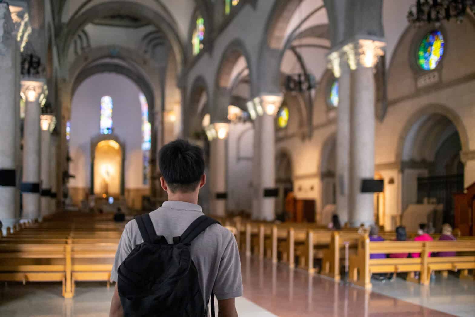 Teenage boy visiting church wearing backpack