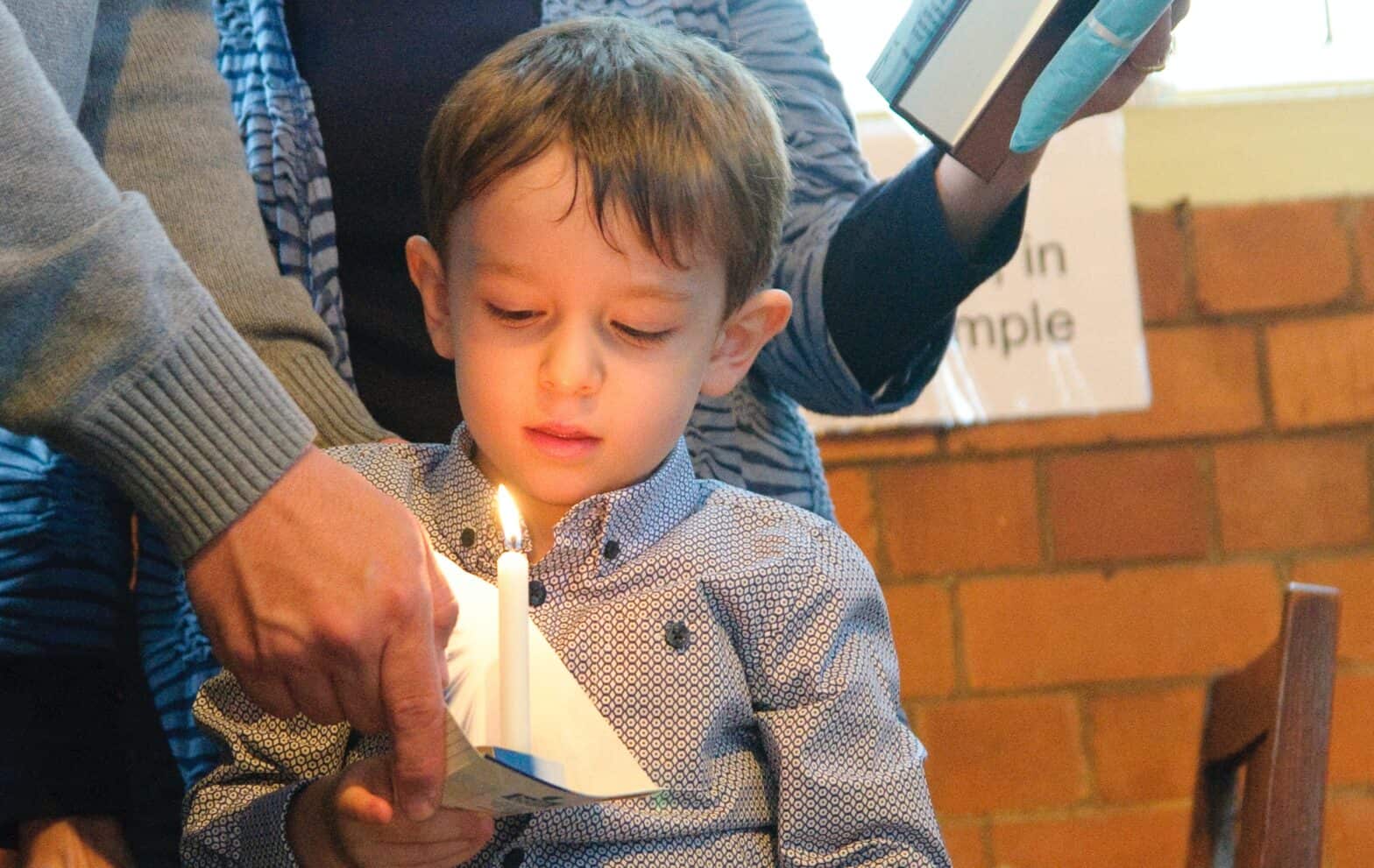 Young boy looking down at a lit candle