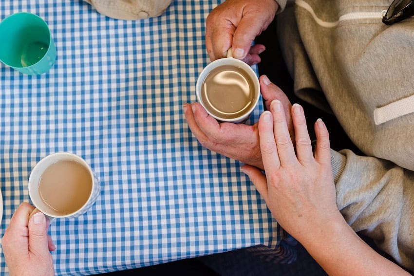 Person offering comfort to another person over a cup of coffee