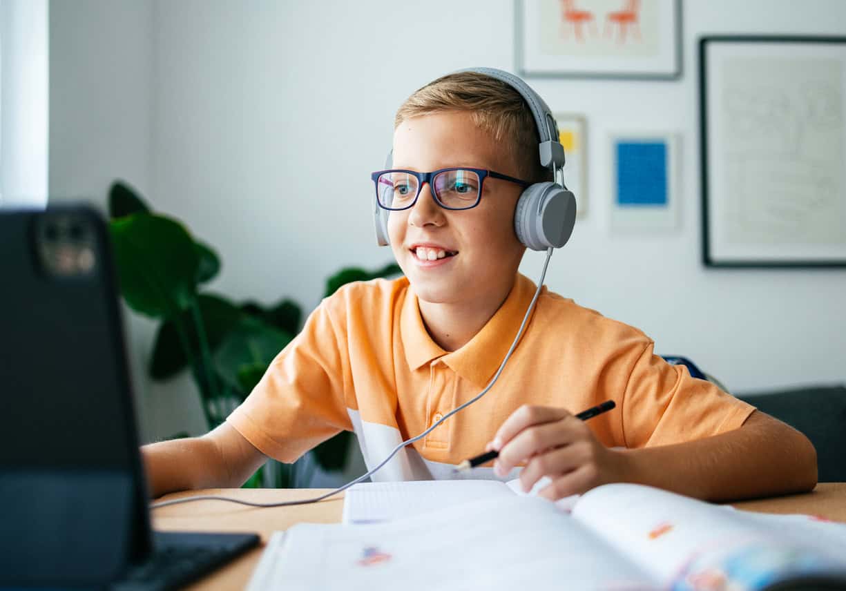 Boy wearing glasses and headphones and playing on a computer