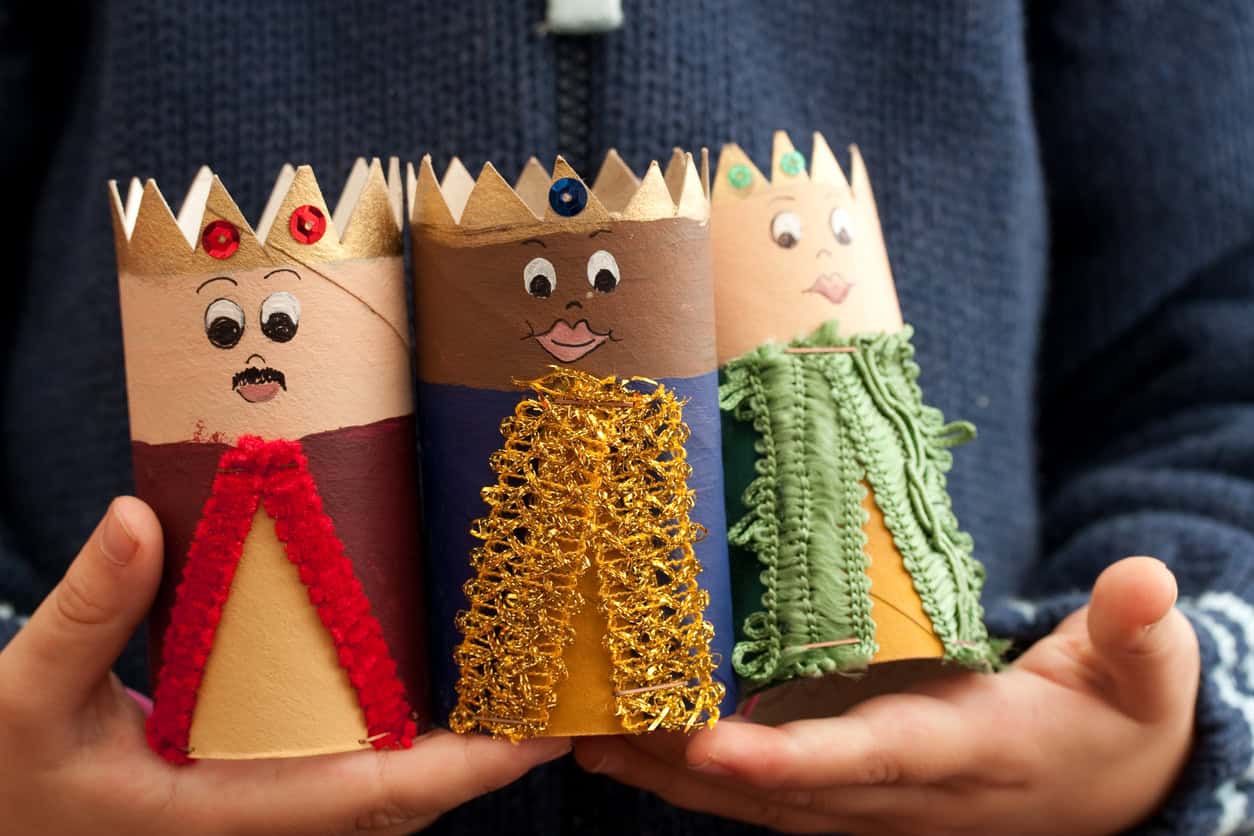 Close up of child's hands holding three home made nativity wise men.
