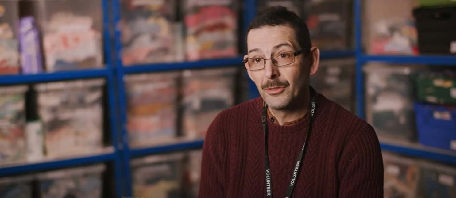 Man sitting in front of boxes of baby clothes at Baby Exchange Centre