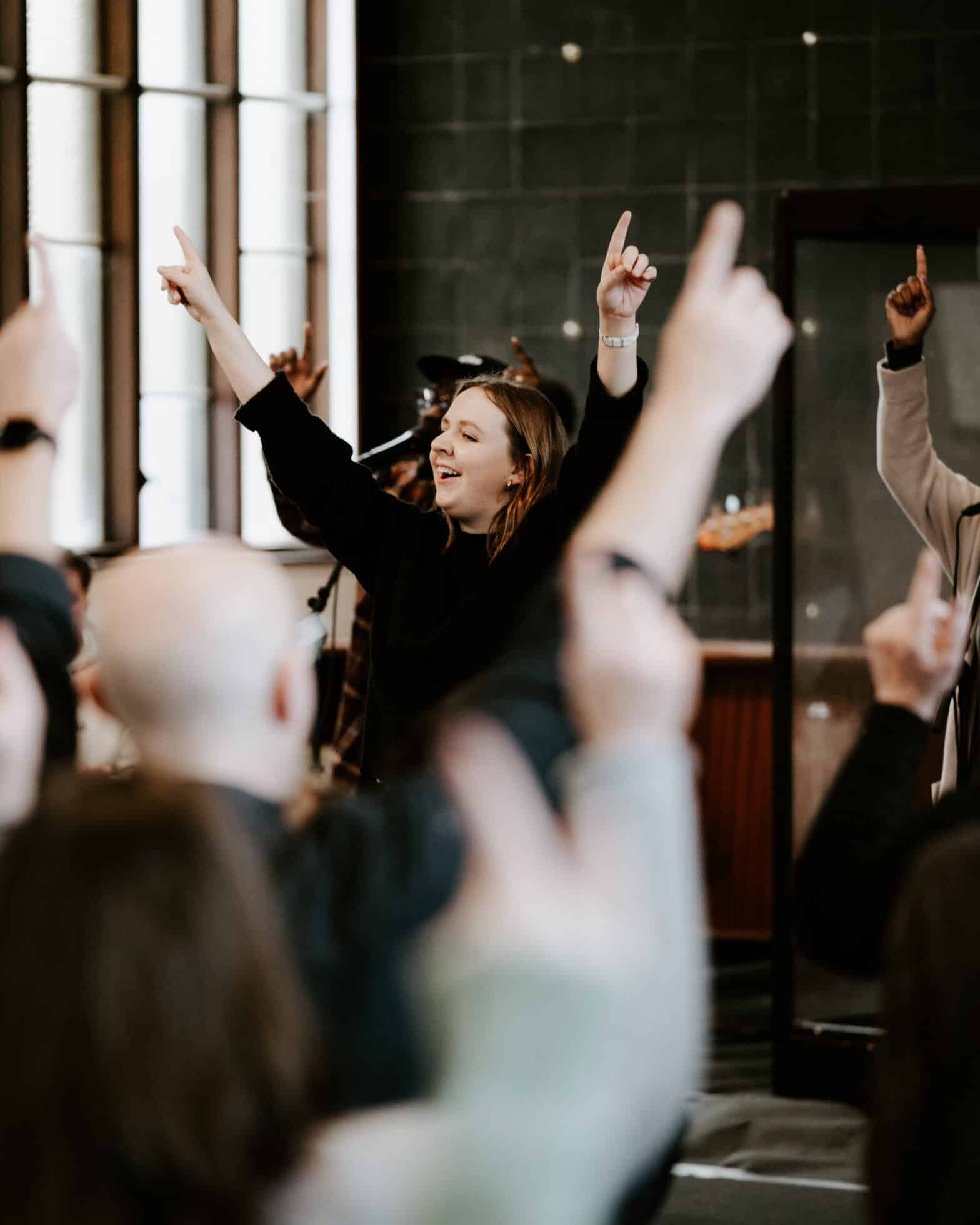 Worshippers at a church with their hands in the air pointing up