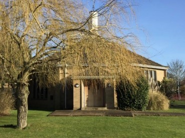 Image of church building with an autumnal tree in front on a day of clear blue skies