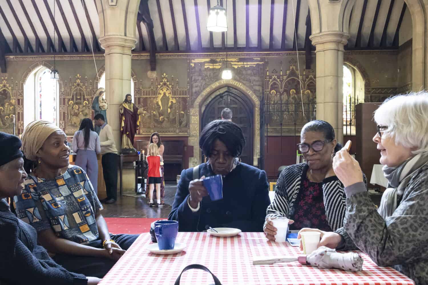 Group of people sitting around a table in a church drinking tea