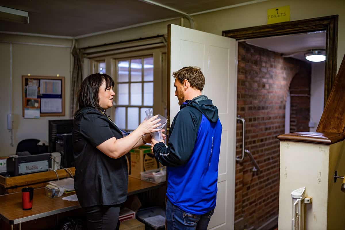 Vicar and man standing in an office and talking
