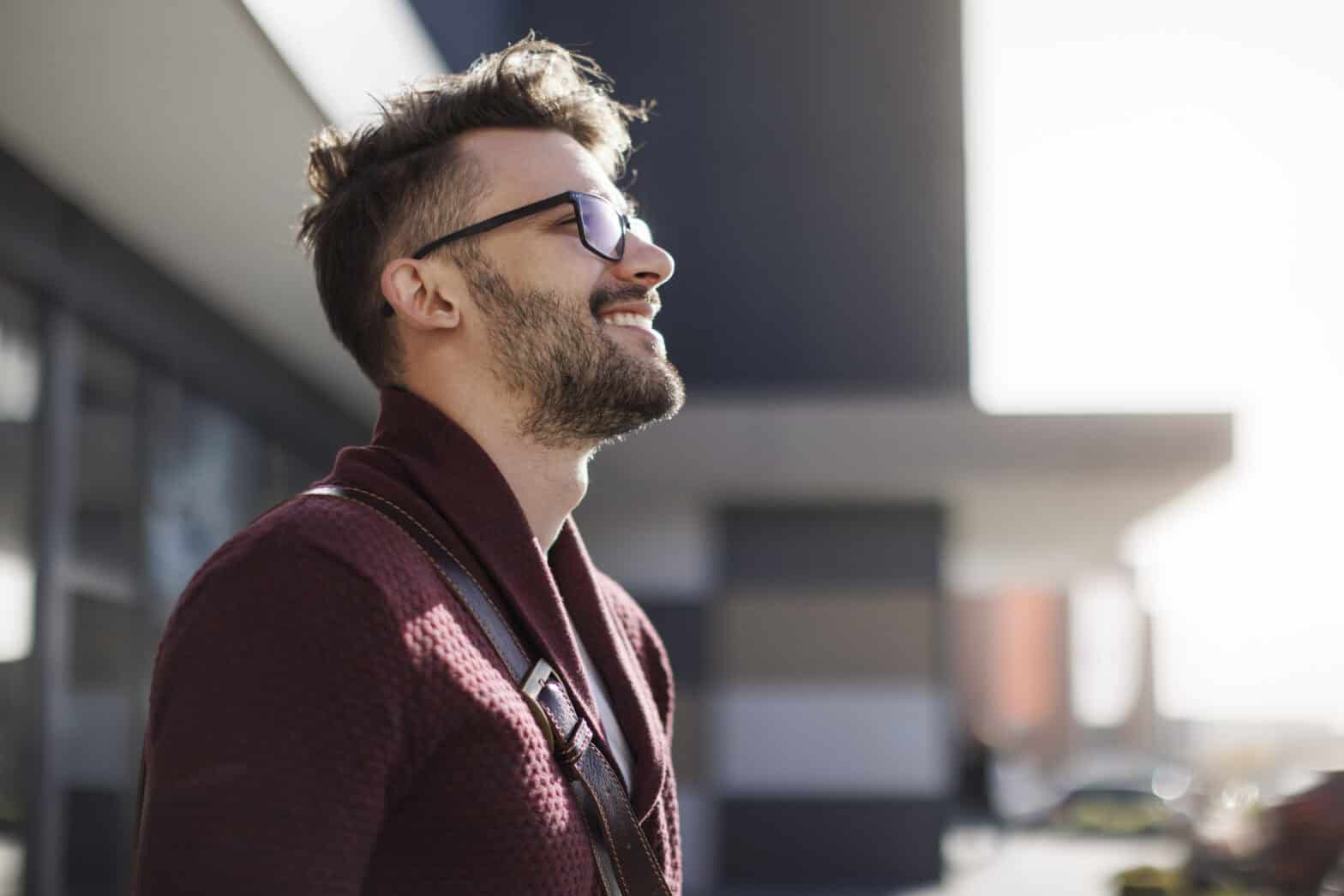 Young man with glasses smiling and looking upwards