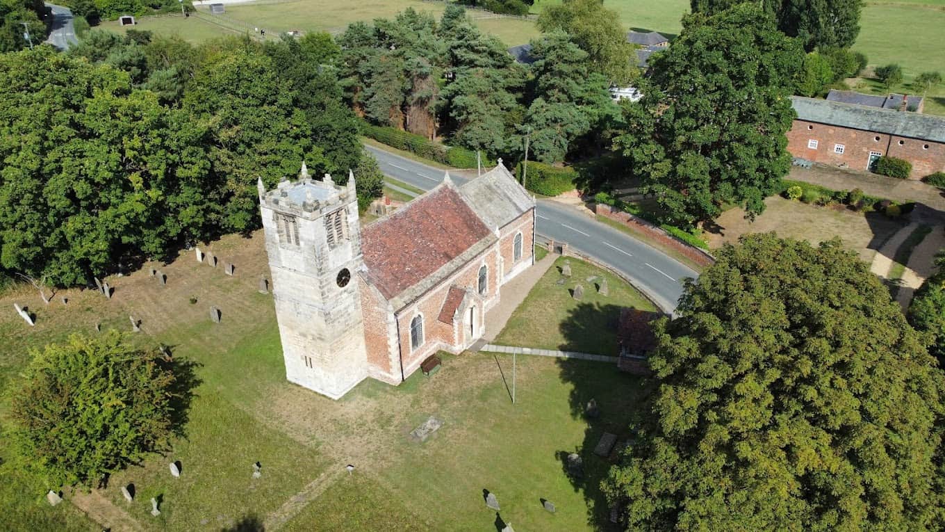 Image of a picturesque church with lots of greenery around taken from a drone