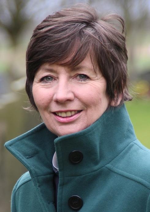 Smiling vicar with dark hair and a green winter coat