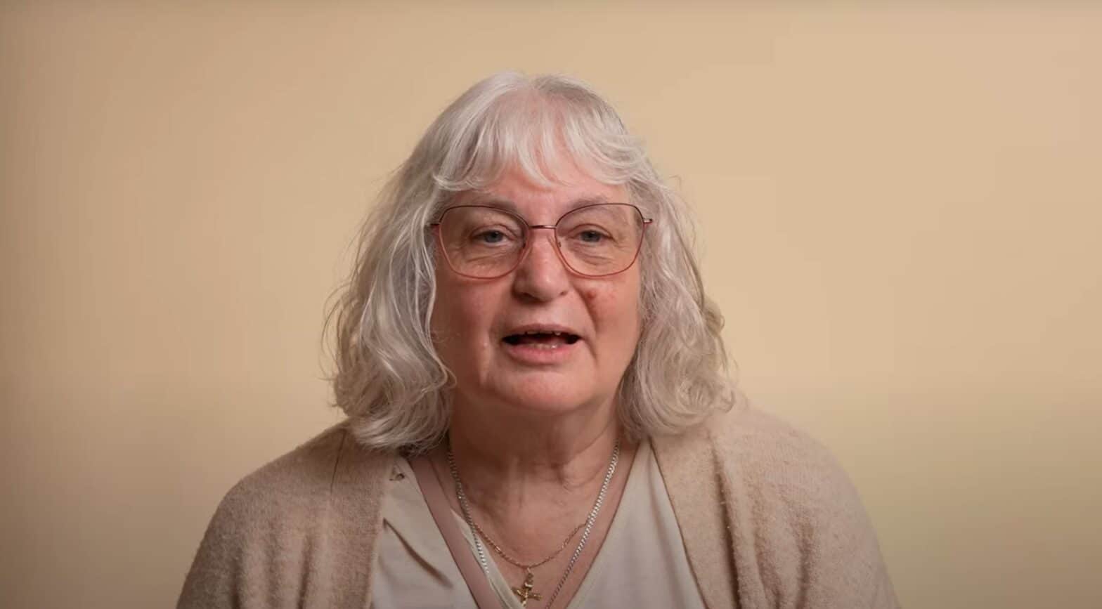 Woman wearing glasses against a beige background
