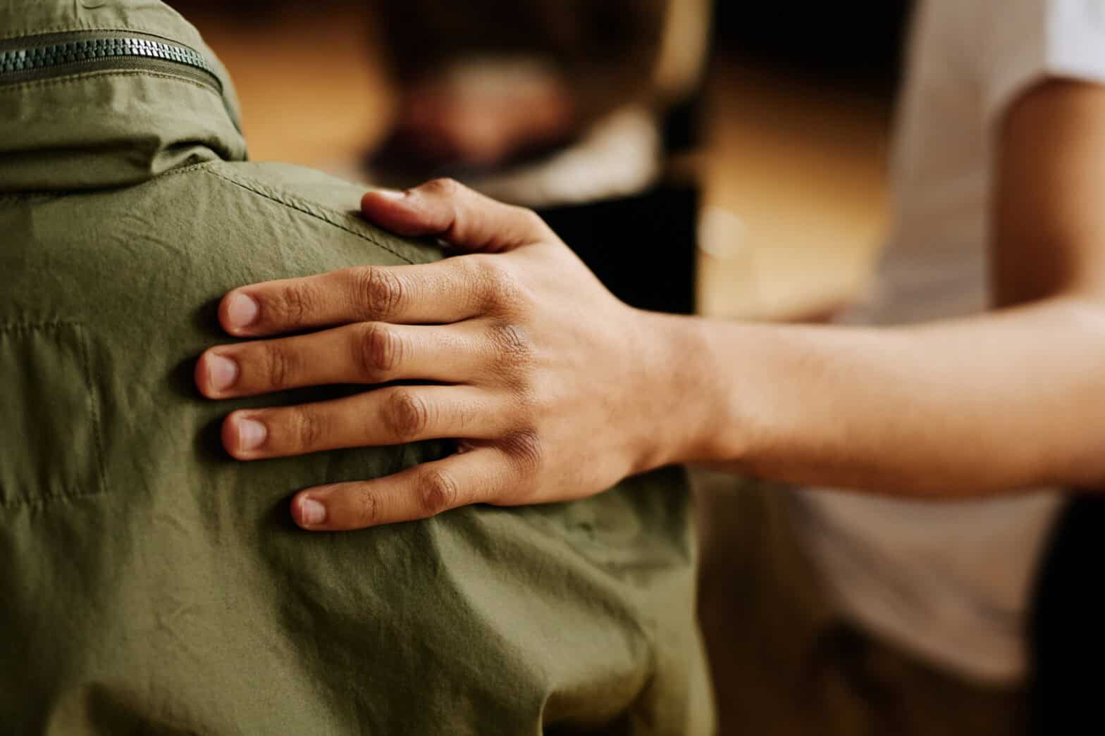 Image of someone's hand on someone else's shoulder in a gesture of comfort