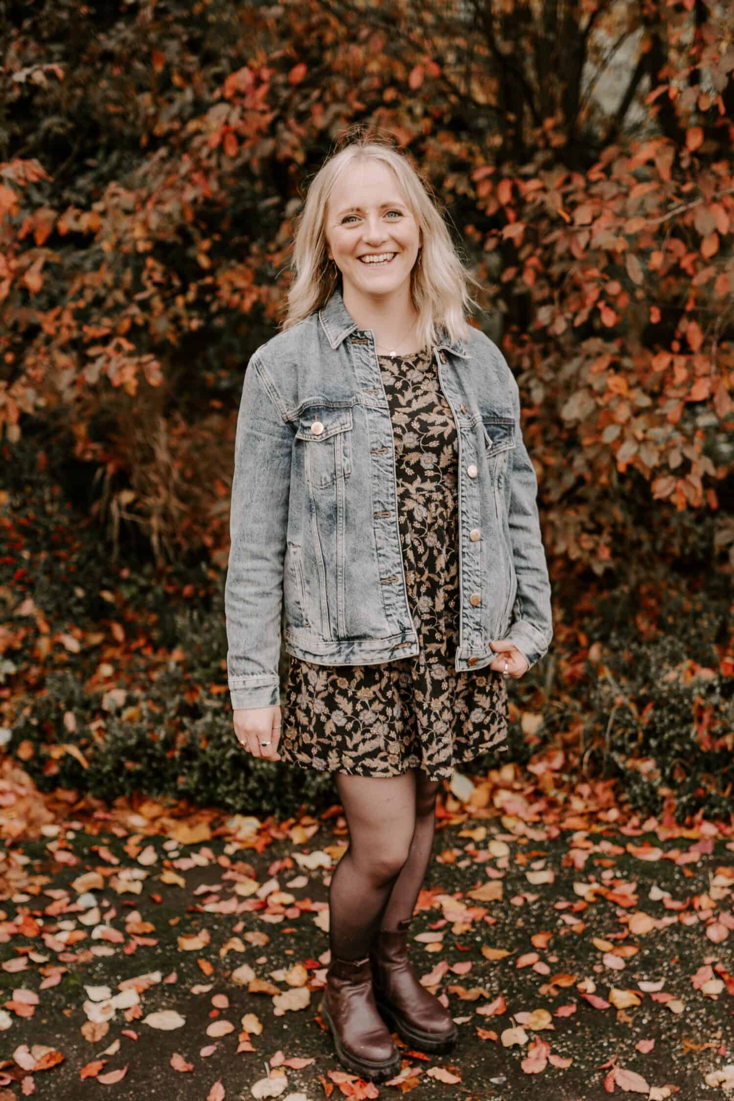 Woman in denim jacket standing in a pile of leaves