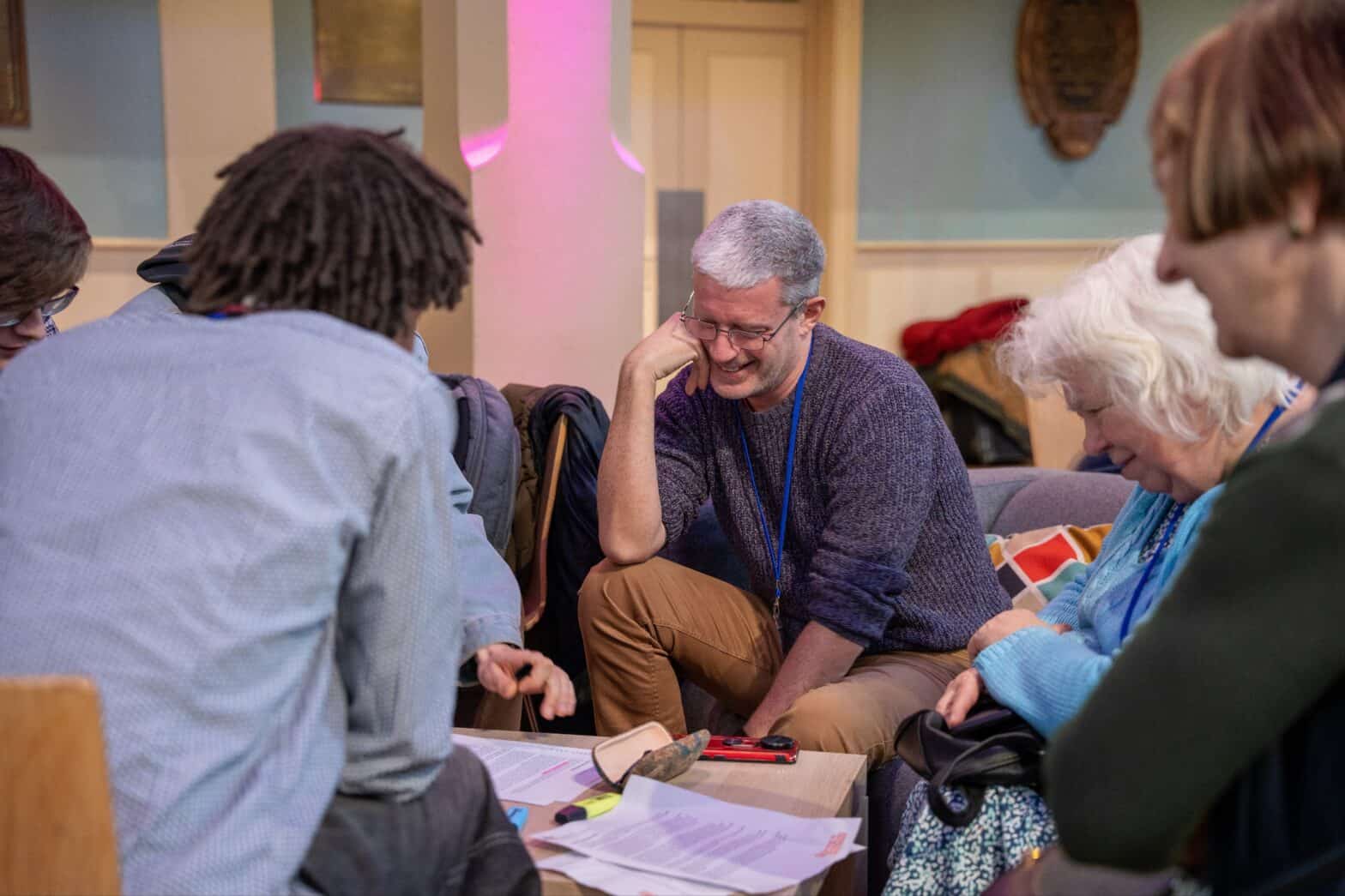 A group of people gathered at a table having a discussion in a conference setting