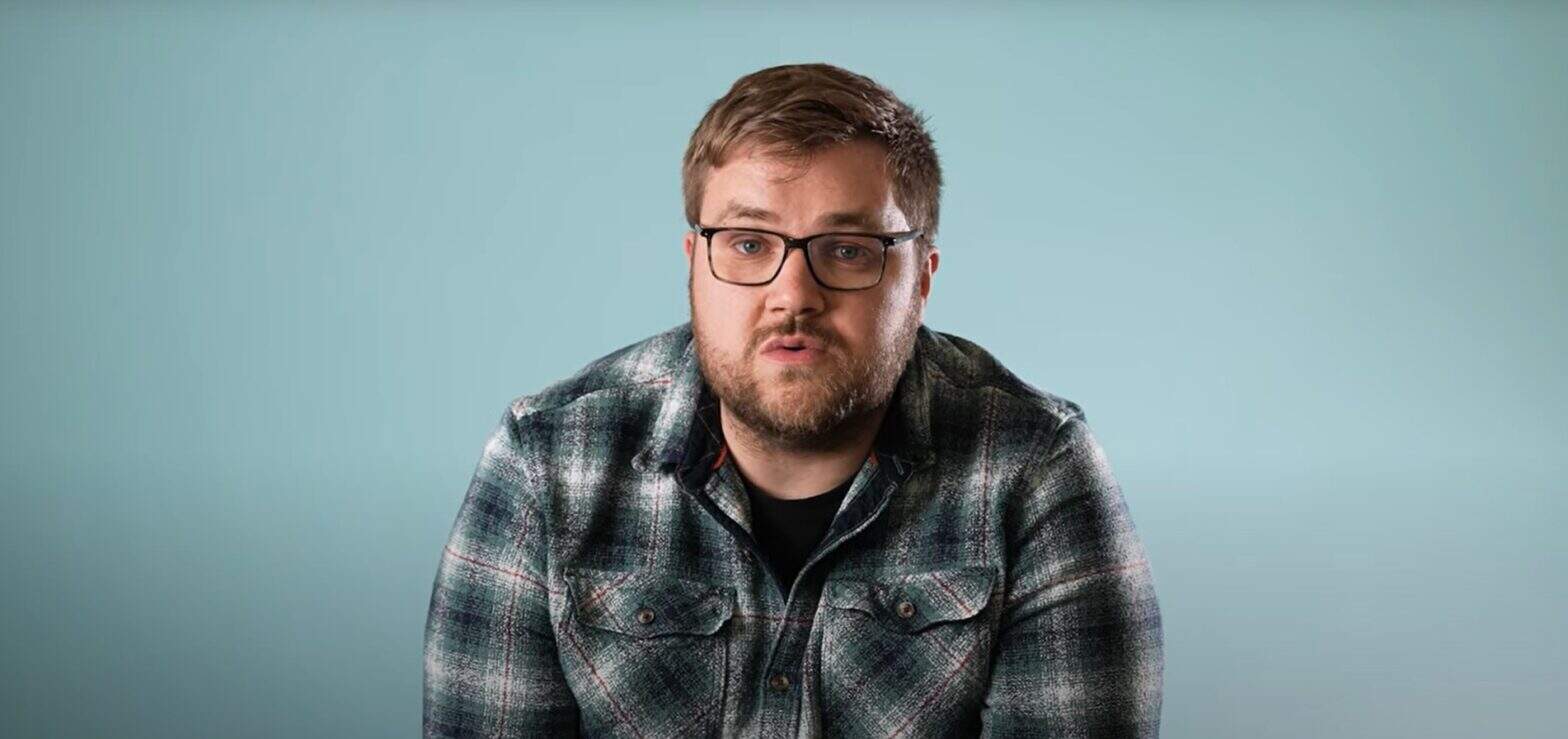 Man wearing glasses and a checked shirt against a blue background