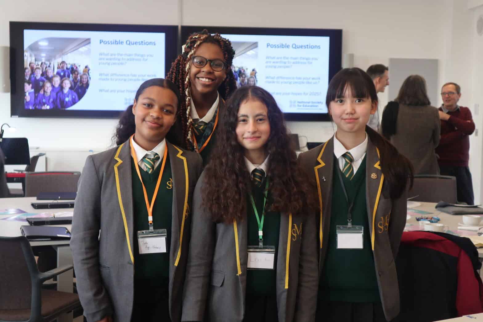 Four students wearing school uniform and lanyards and smiling