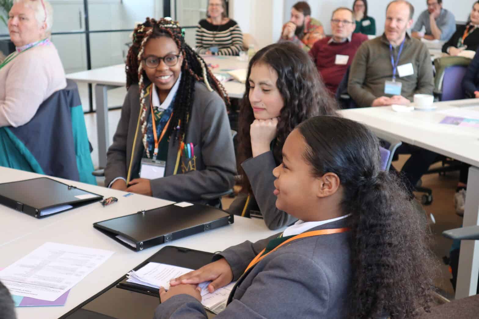 Three students sitting around a desk and discussing a Growing Faith topic