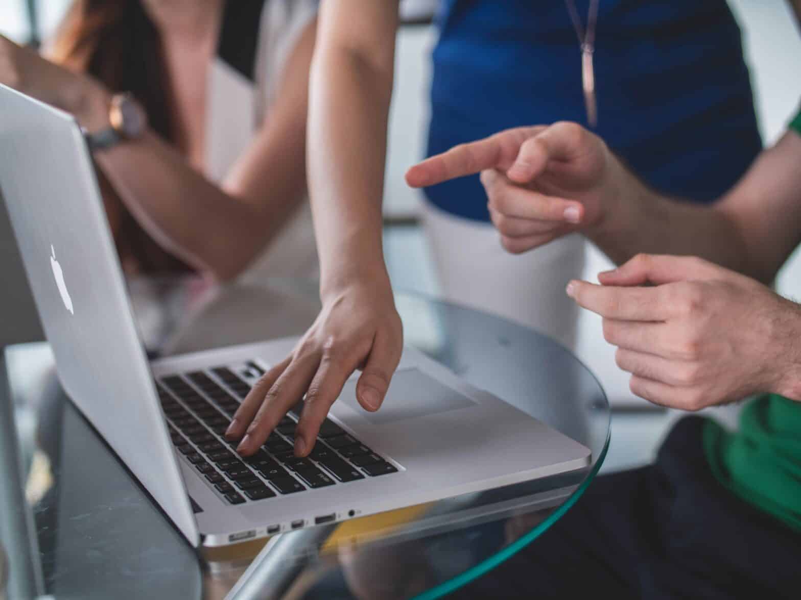 a group of people with no faces showing working together looking at a laptop