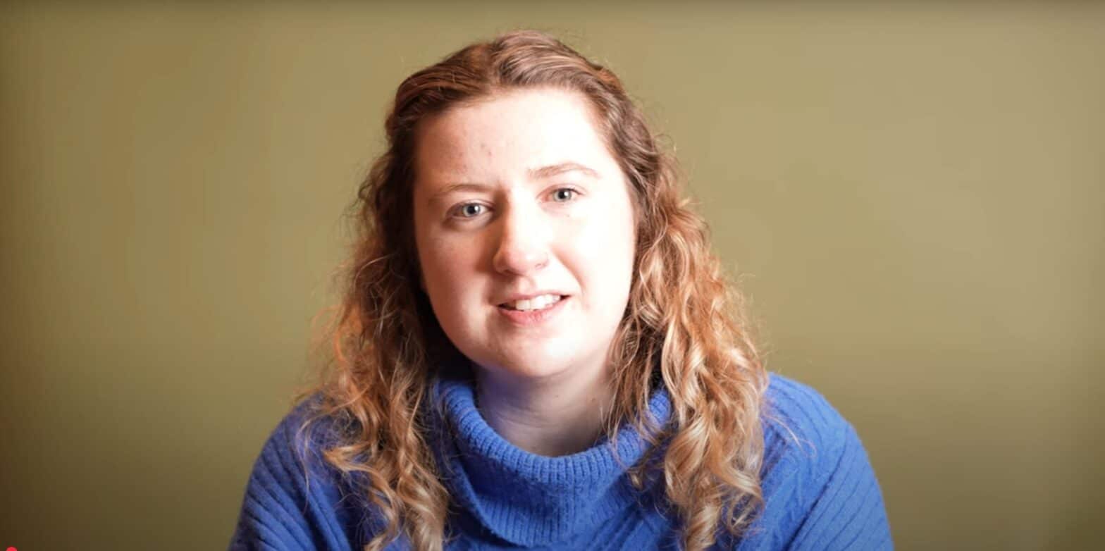 Woman wearing a blue jumper presents against an olive background