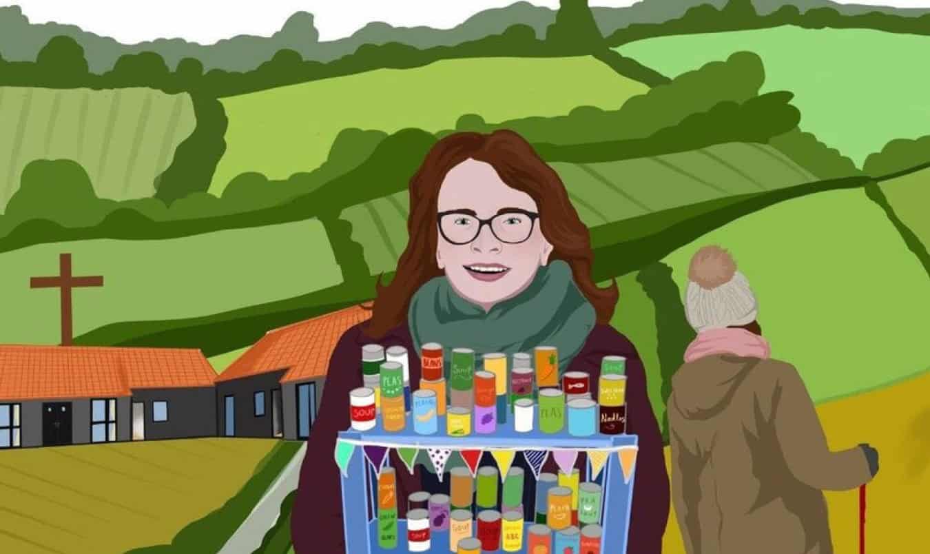 Woman standing in front of a collection of food, with another in the background with a walking stick. There are rolling green fields in the background, separated by hedges, and a cross atop a non-traditional church.