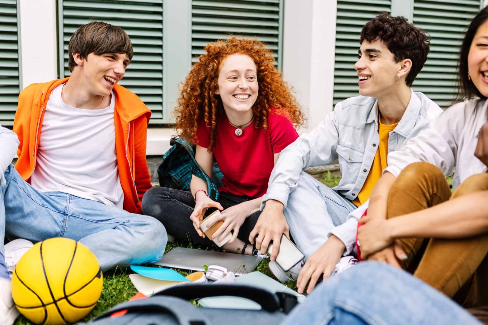 Young people at a youth group sitting in a circle and laughing together. There is a ball for activities.