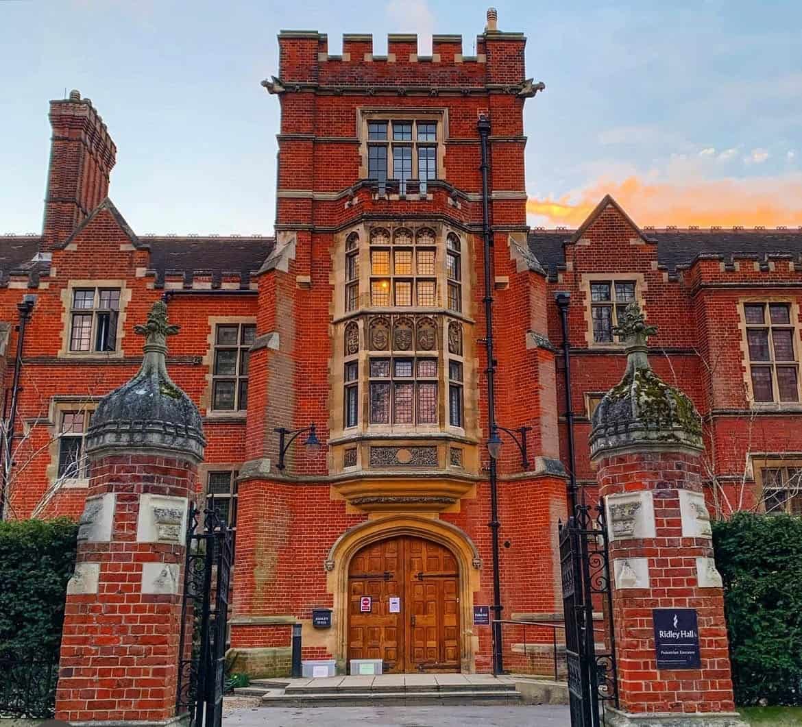 Historical red brick building with a large wooden door with a gate in front