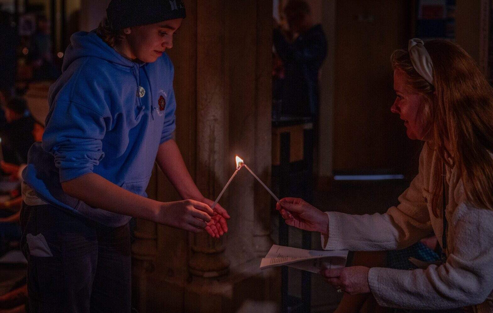 Two women sharing a candle flame