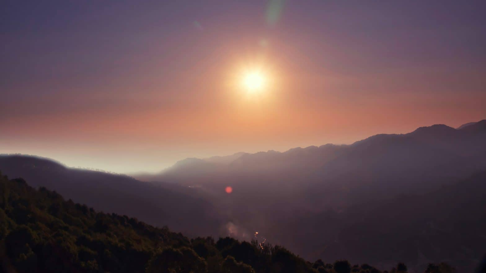 Sun in sky against mountain horizon