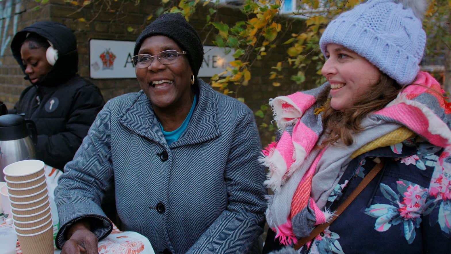 Two women wrapped up in warm clothes are getting hot drinks