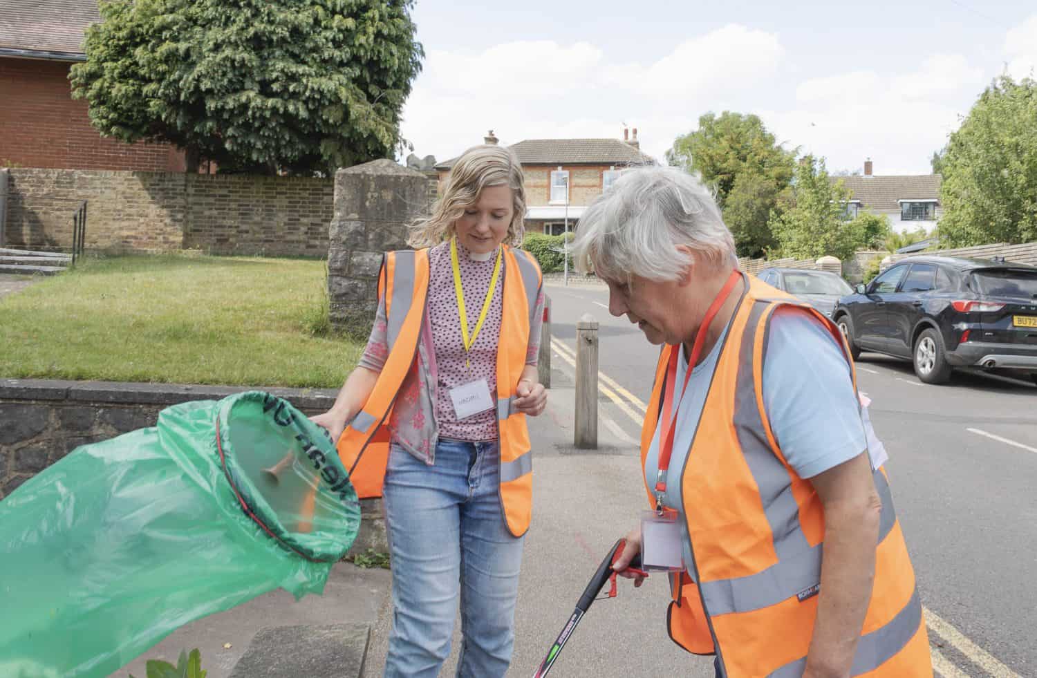 Two women are outside doing a litter pick in a neighbourhood