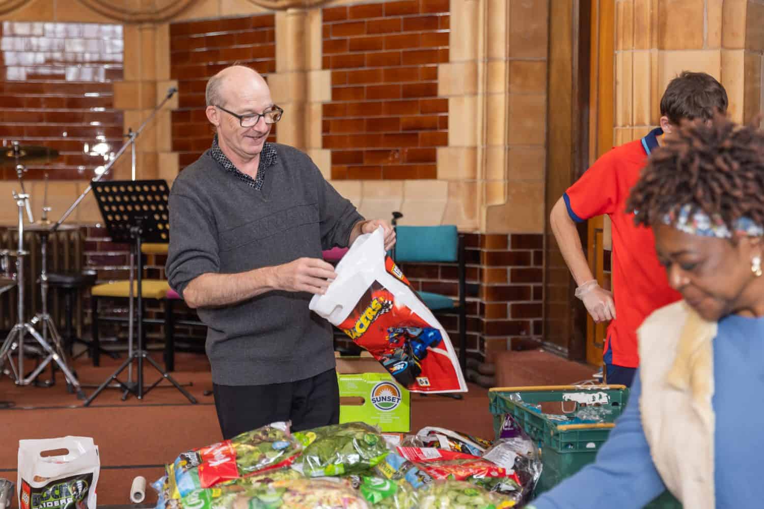 Man helping at a food bank and holding a bag open to put food into it