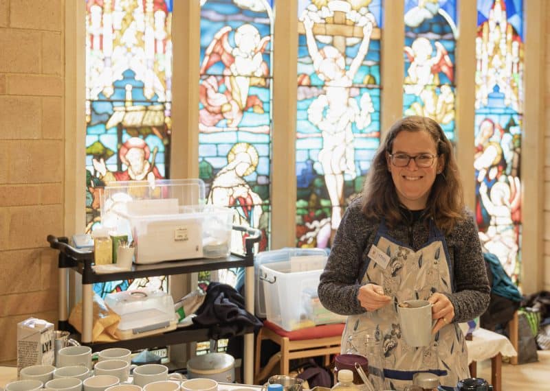 Smiling woman making a cup of coffee for someone in a church