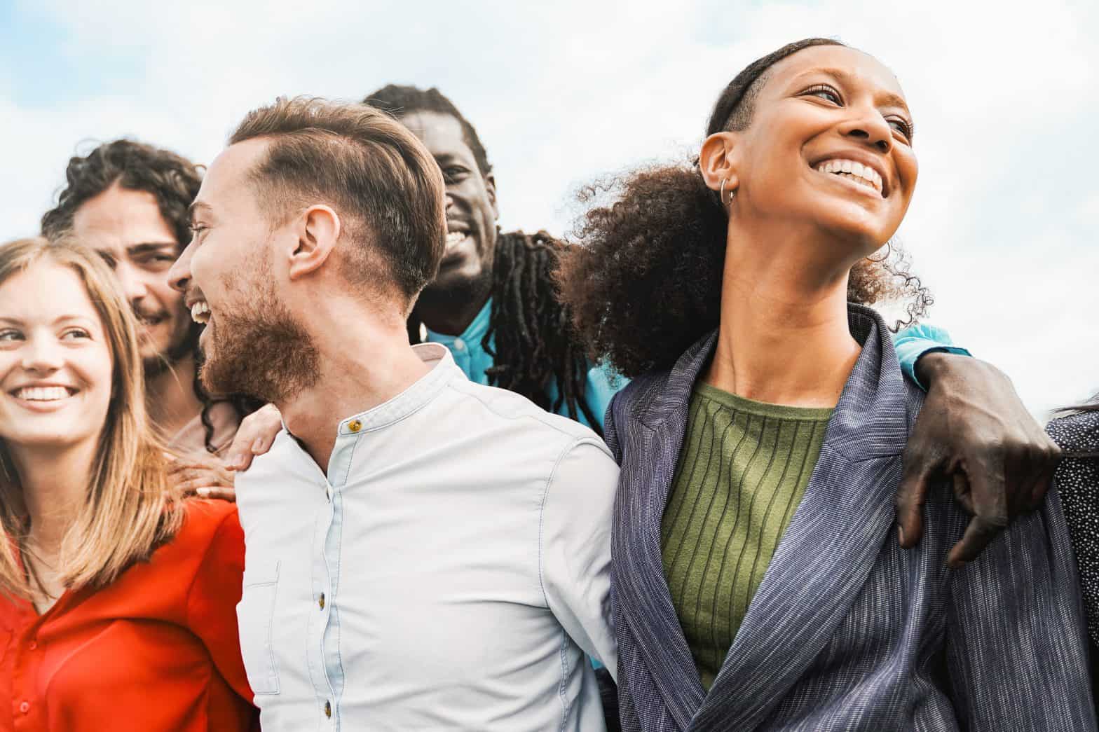 A group of young adults smiling and laughing, with their arms around each other